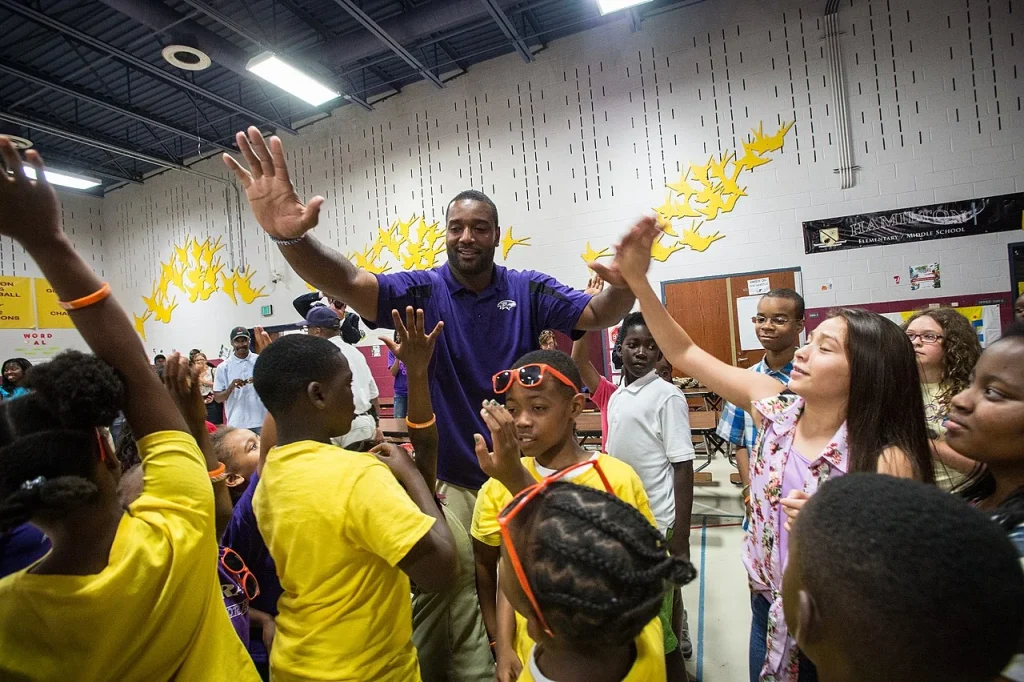 Chris Canty giving high fives to children at a youth development community event.