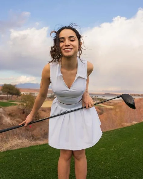 Content creator posing with golf club in athletic wear on golf course