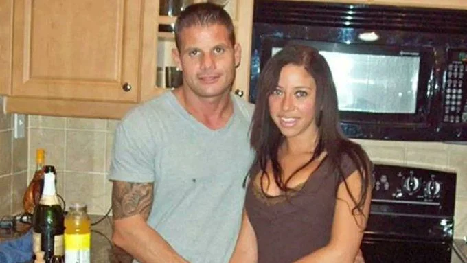 A pre-arrest snapshot of Michael Dippolito and Dalia Dippolito smiling together while standing in a kitchen with wooden cabinets.
