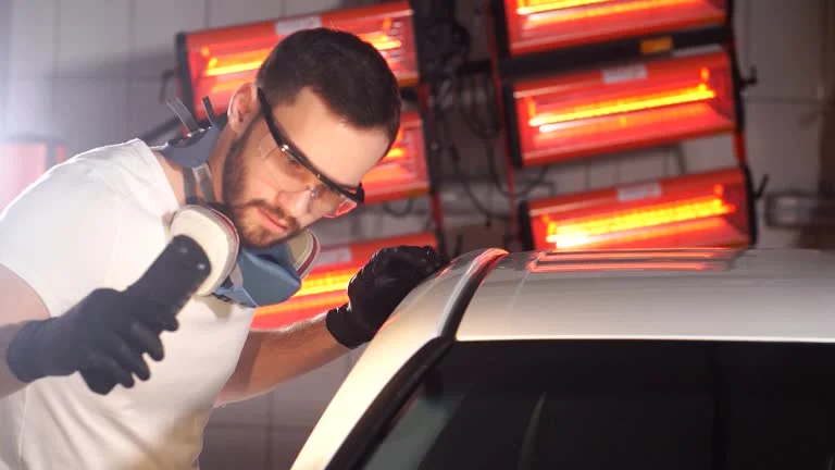 Technician using Ausbeulstation for paintless dent repair on a car panel