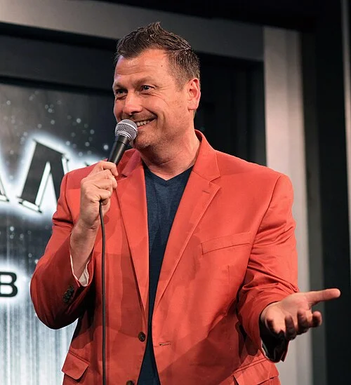 Jimmy Failla performing stand-up comedy in an orange blazer at Gotham Comedy Club New York